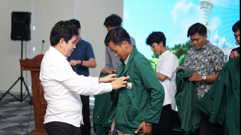 Dekan FEBI UIN RIL, Prof Tulus lakukan penyematan jaket almamater sebagai tanda pelepasan mahasiswa magang internasional.