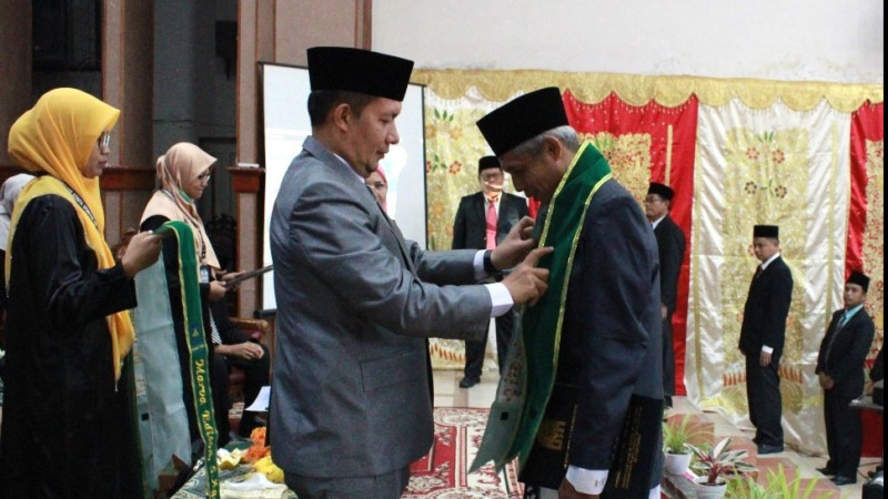 Prof. Dr. Marjoni Imamora, M.Sc Memasangkan Salempang Kepada Peserta Pengukuhan Guru Profesional