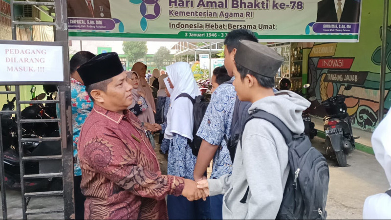 Kepala MTsN 2 Padang Pariaman, Suhaimis, didampingi majelis guru, menyambut kedatangan siswa dengan sapaan menggunakan bahasa Arab.